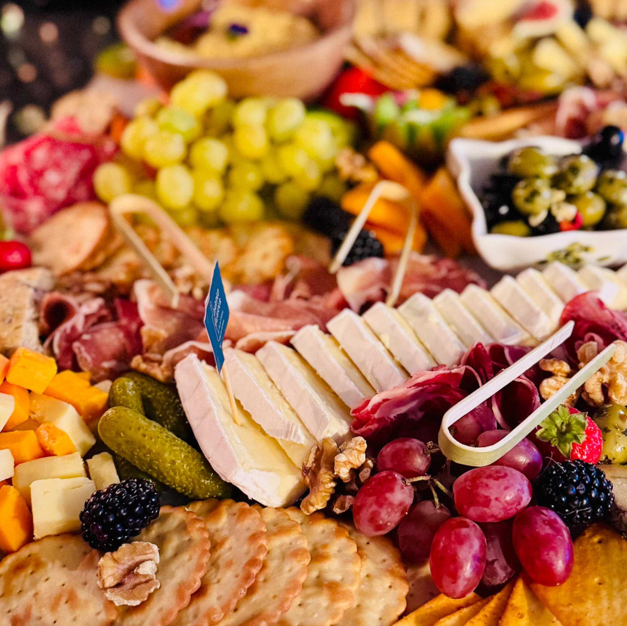 A close up of charcuterie a close up of some humous, grapes, breads, strawberries, peppers and figs